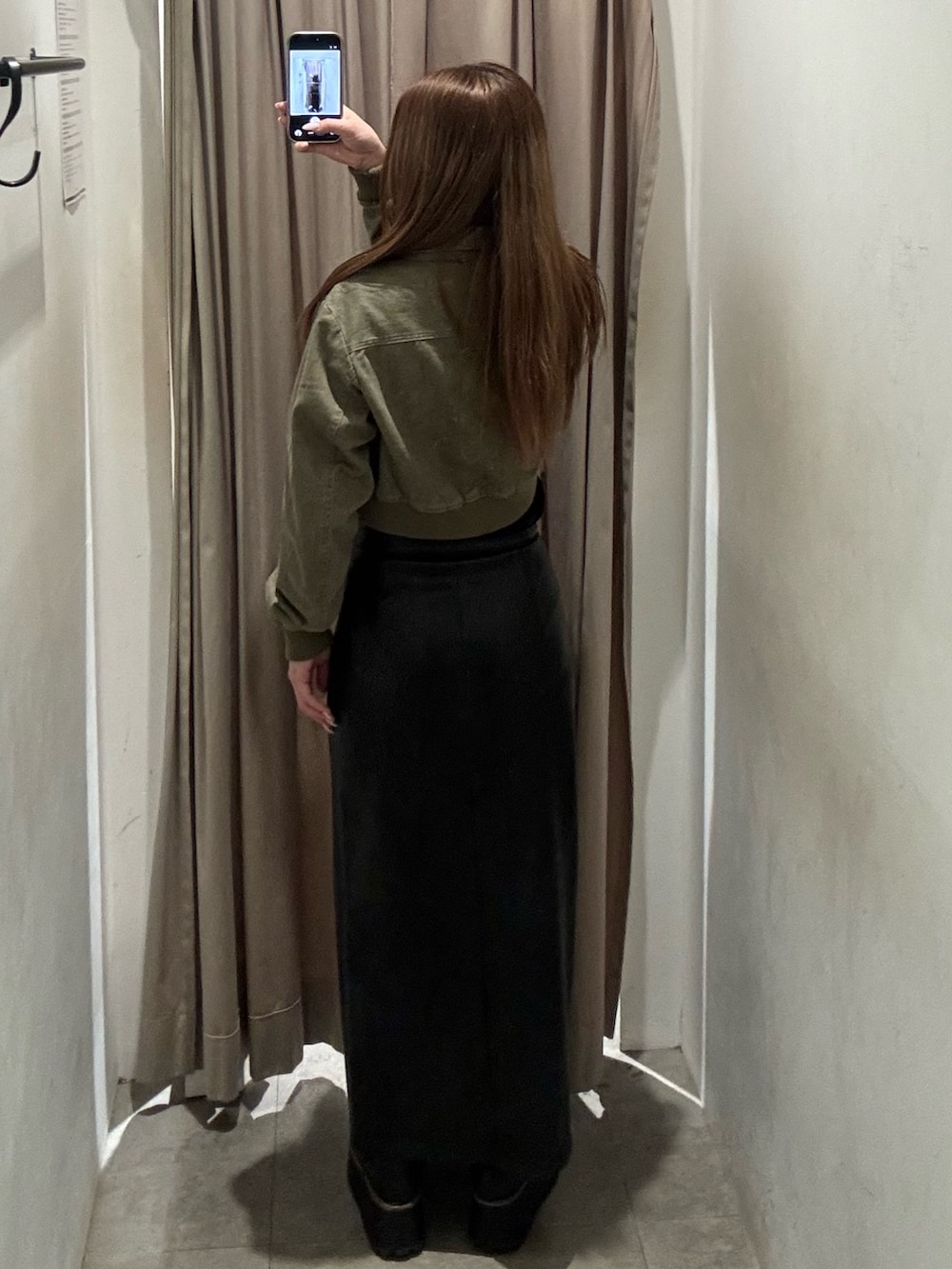 ブラック系のスカート、グリーン系のブルゾン、ブラック系のブーツを着用したレディースの春コーディネートの3枚目の写真