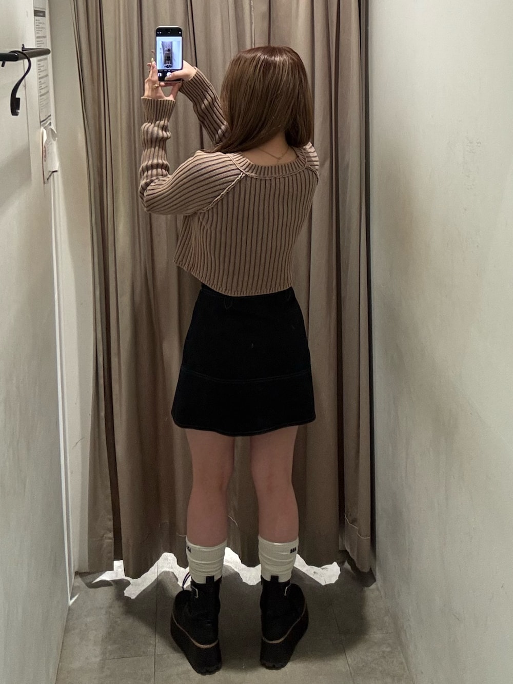 ブラック系のスカート、ベージュ系のニット/セーター、ブラック系のブーツを着用したレディースの冬コーディネートの3枚目の写真