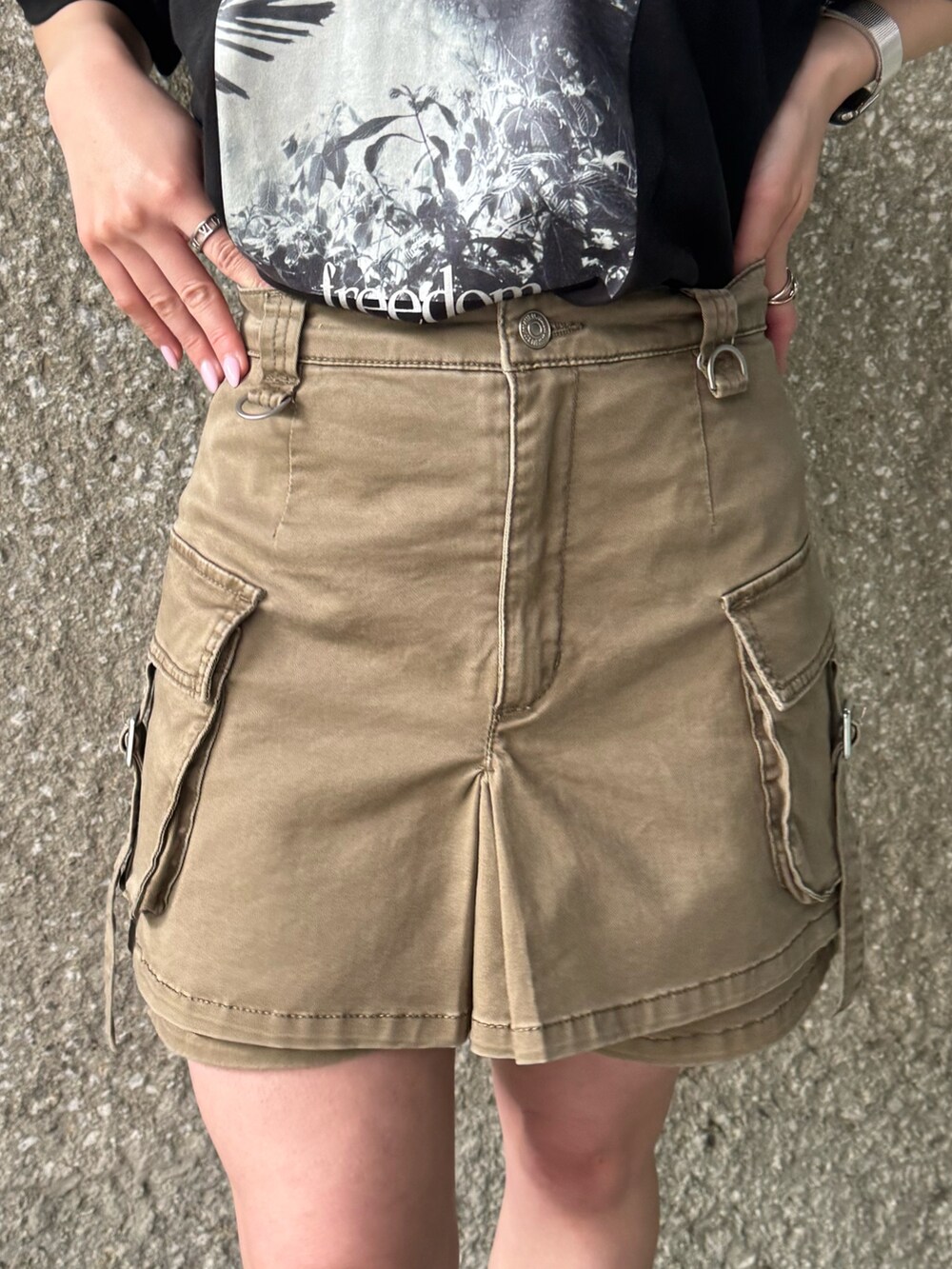 ブラック系のTシャツ/カットソー、ベージュ系のスカート、ブラック系のブーツを着用したレディースの春コーディネートの6枚目の写真