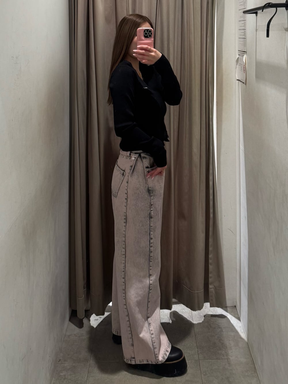 ピンク系のデニムパンツ、ブラック系のニット/セーター、ブラック系のブーツを着用したレディースの春コーディネートの2枚目の写真