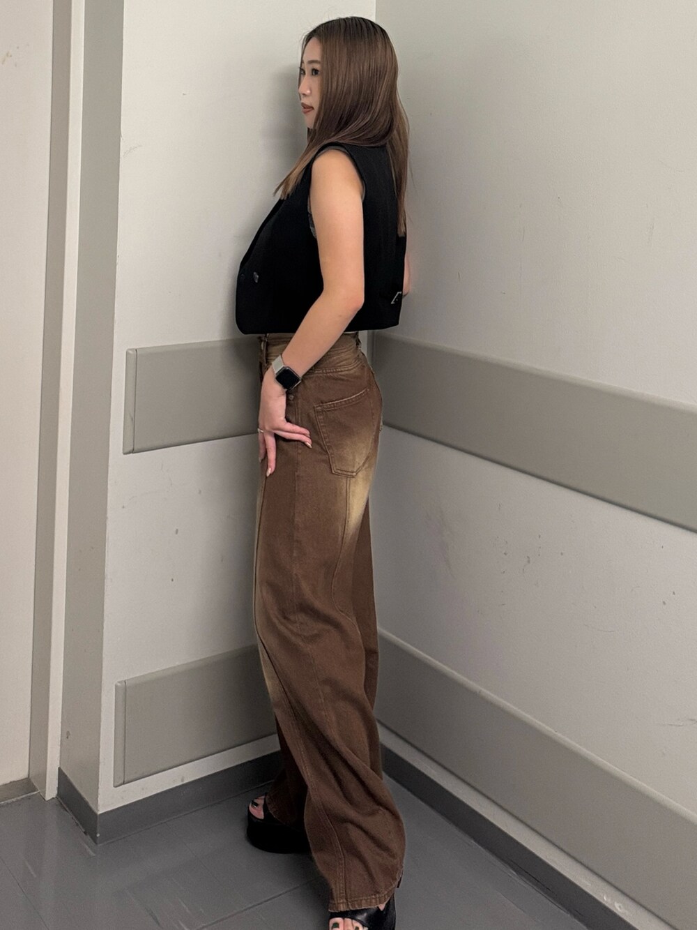 ブラウン系のデニムパンツ、グレー系のタンクトップ、ブラック系のベストを着用したレディースの夏コーディネートの2枚目の写真