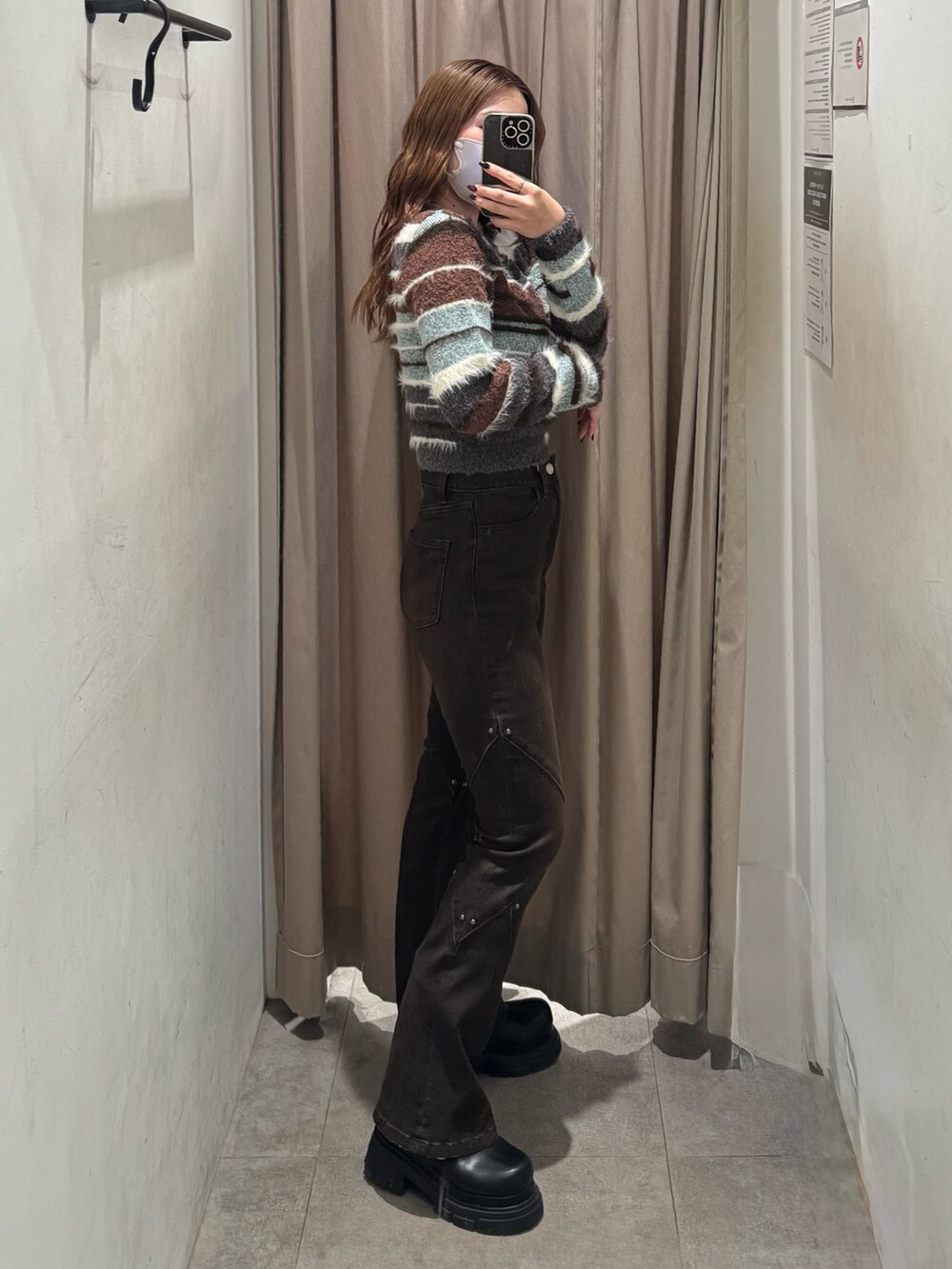 ブラウン系のデニムパンツ、ブラウン系のニット/セーター、ブラック系のブーツを着用したレディースの秋コーディネートの2枚目の写真