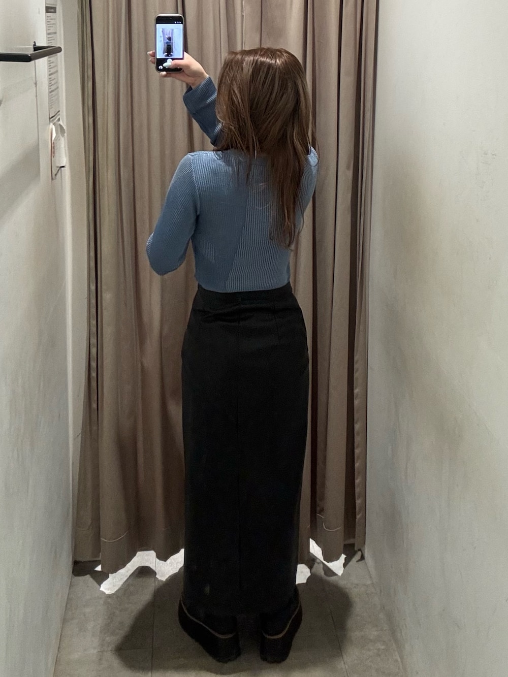 ブルー系のニット/セーター、ブラック系のスカート、ブラック系のブーツを着用したレディースの冬コーディネートの3枚目の写真