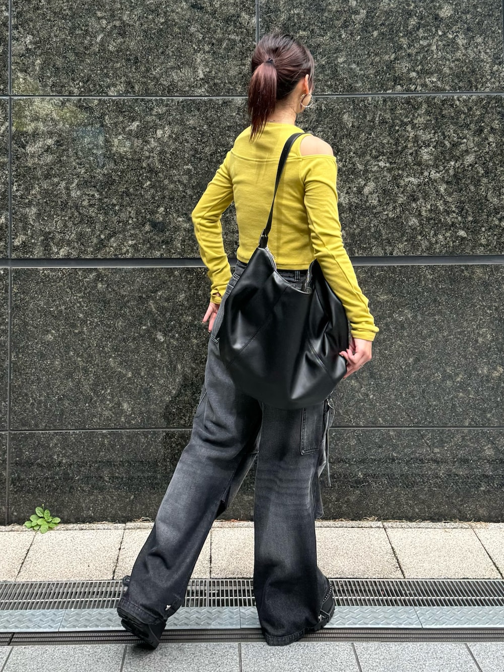イエロー系のTシャツ/カットソー、ブラック系のデニムパンツ、ブラック系のブーツを着用したレディースの秋コーディネートの3枚目の写真