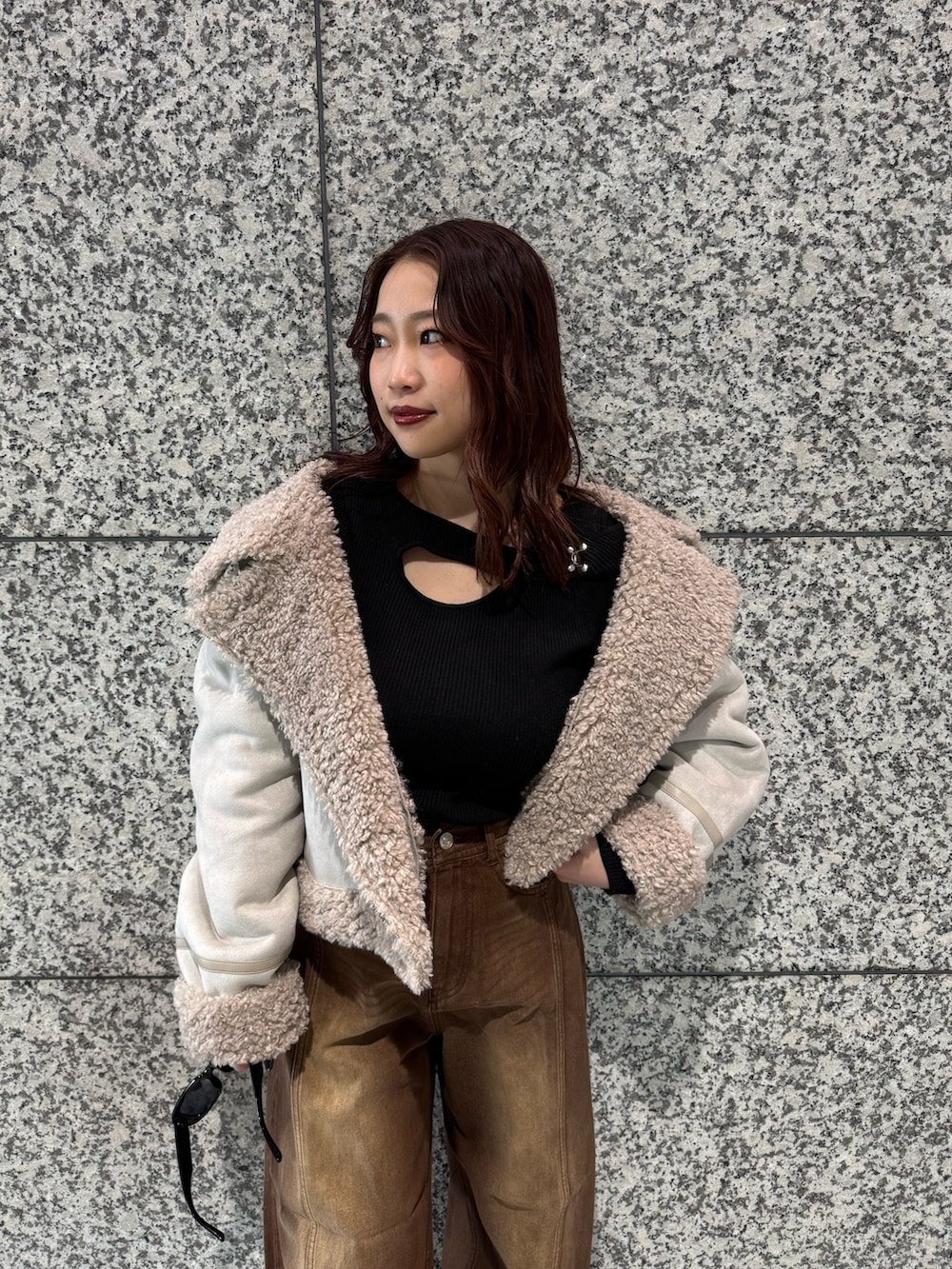 ブラック系のニット/セーター、ホワイト系のムートンコート、ブラウン系のデニムパンツを着用したレディースの冬コーディネートの5枚目の写真