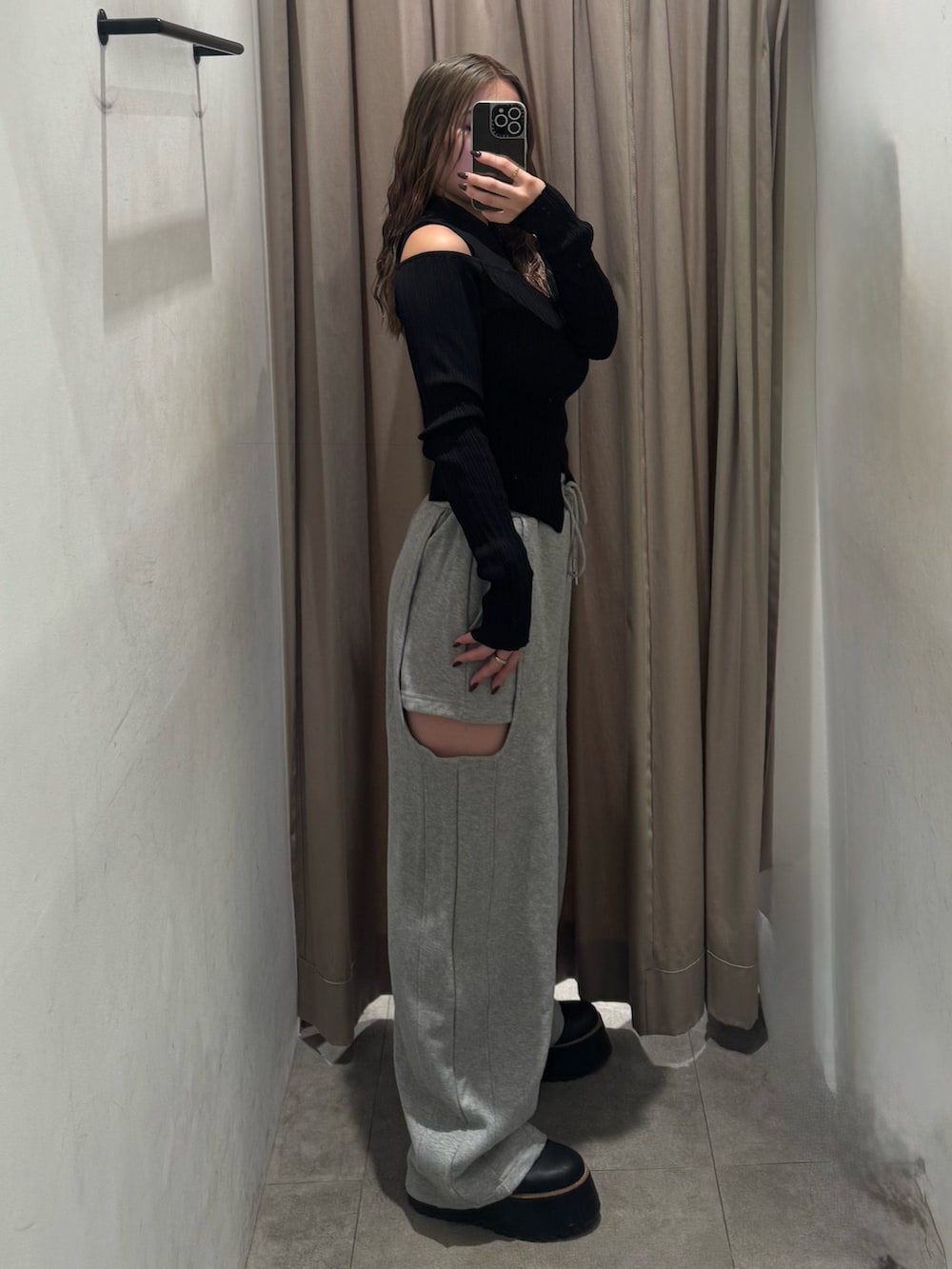 グレー系のスウェットパンツ、ブラック系のニット/セーター、ブラック系のブーツを着用したレディースの秋コーディネートの2枚目の写真