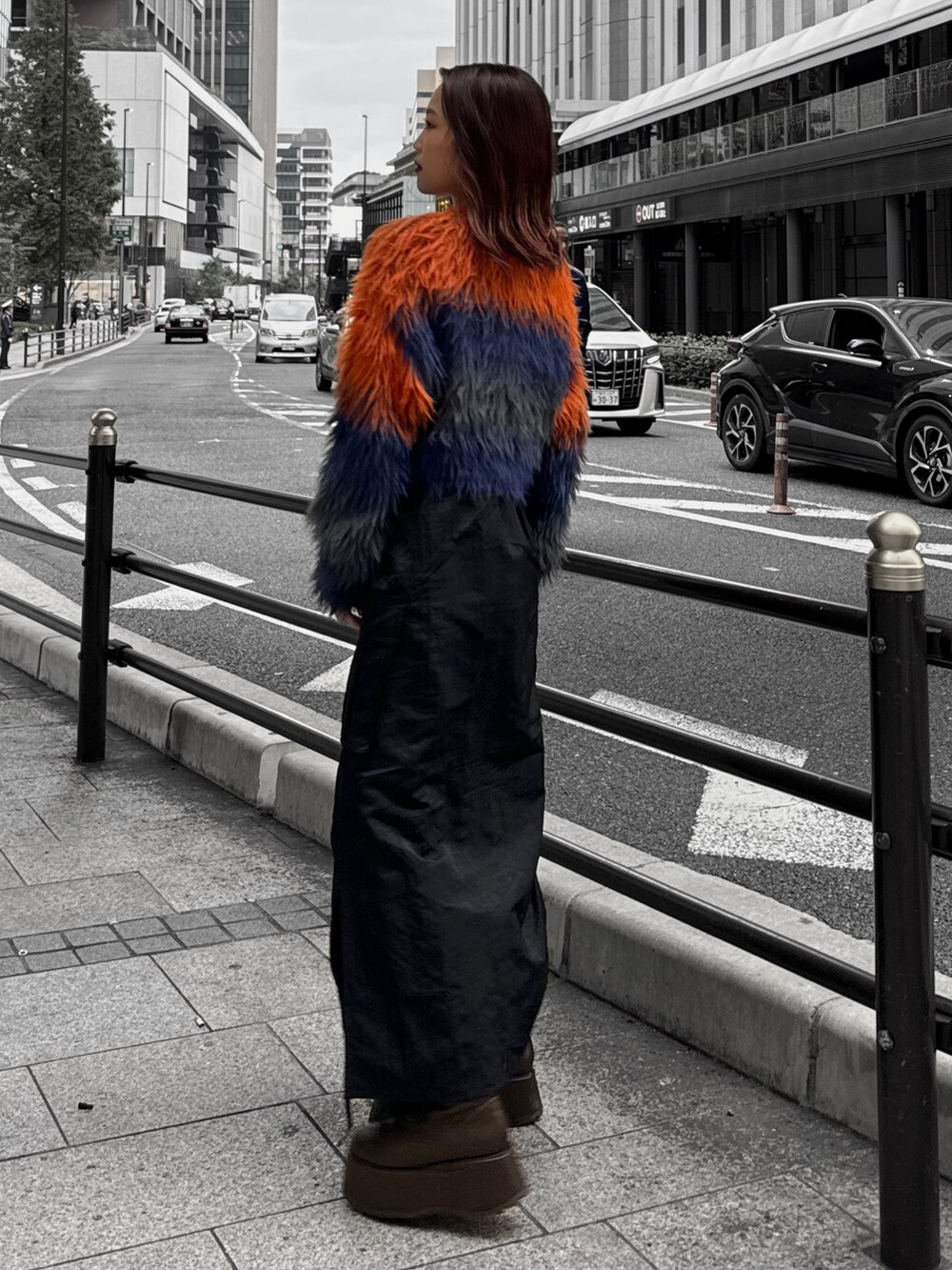 オレンジ系のニット/セーター、ブラック系のスカート、ブラウン系のブーツを着用したレディースの秋コーディネートの3枚目の写真