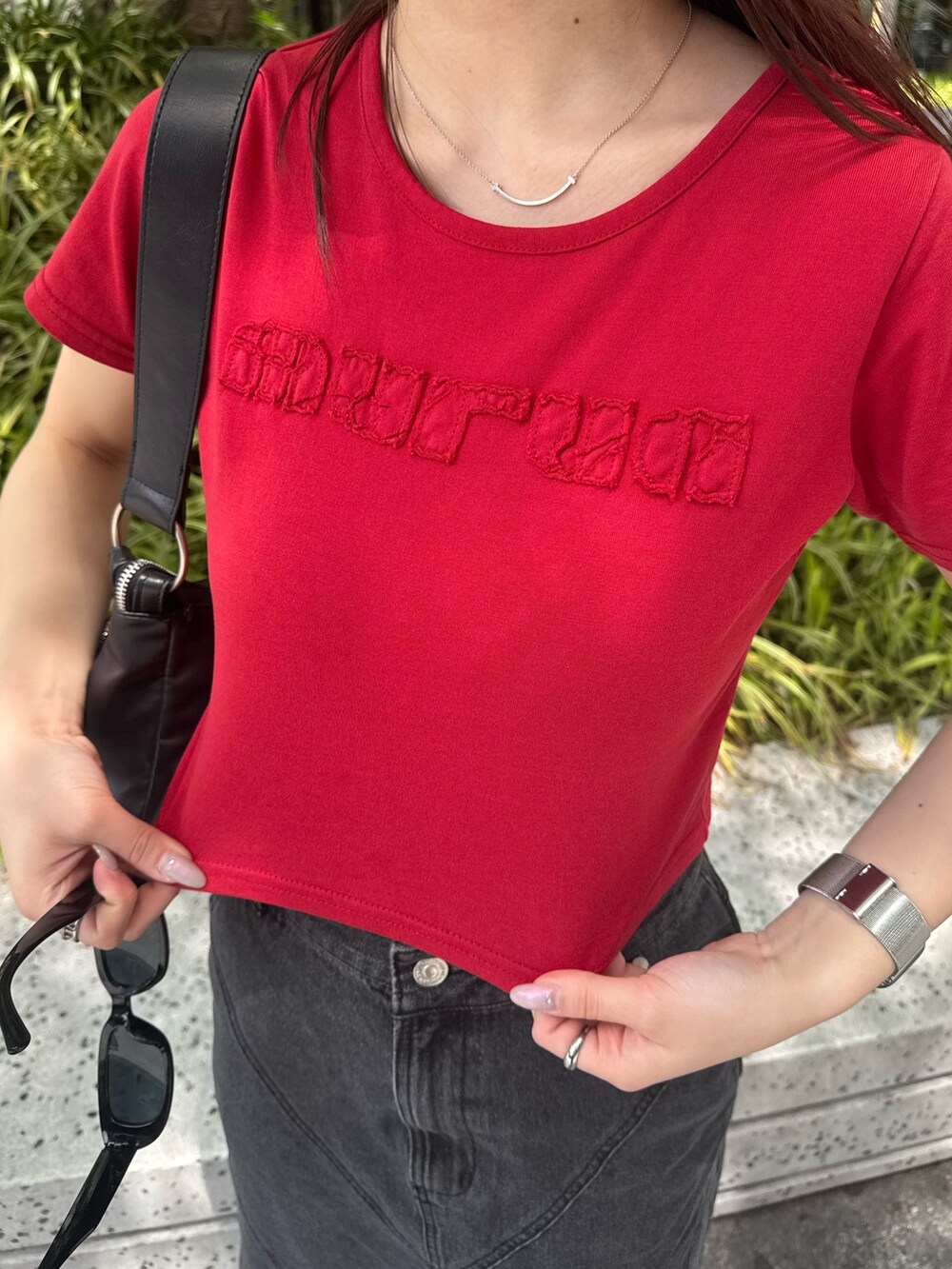 レッド系のTシャツ/カットソー、ブラック系のデニムスカート、ブラック系のブーツを着用したレディースの春コーディネートの5枚目の写真