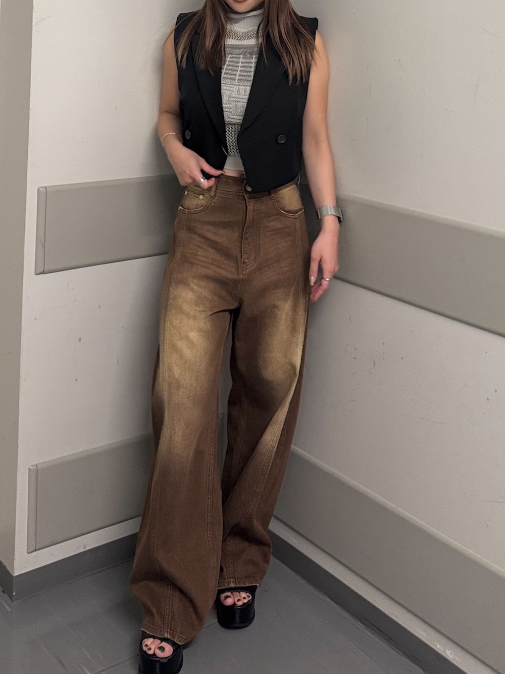 ブラウン系のデニムパンツ、グレー系のタンクトップ、ブラック系のベストを着用したレディースの夏コーディネートの6枚目の写真