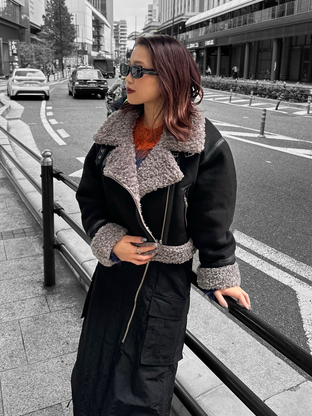 ブラック系のムートンコート、オレンジ系のニット/セーター、ブラック系のスカートを着用したレディースの冬コーディネートの4枚目の写真
