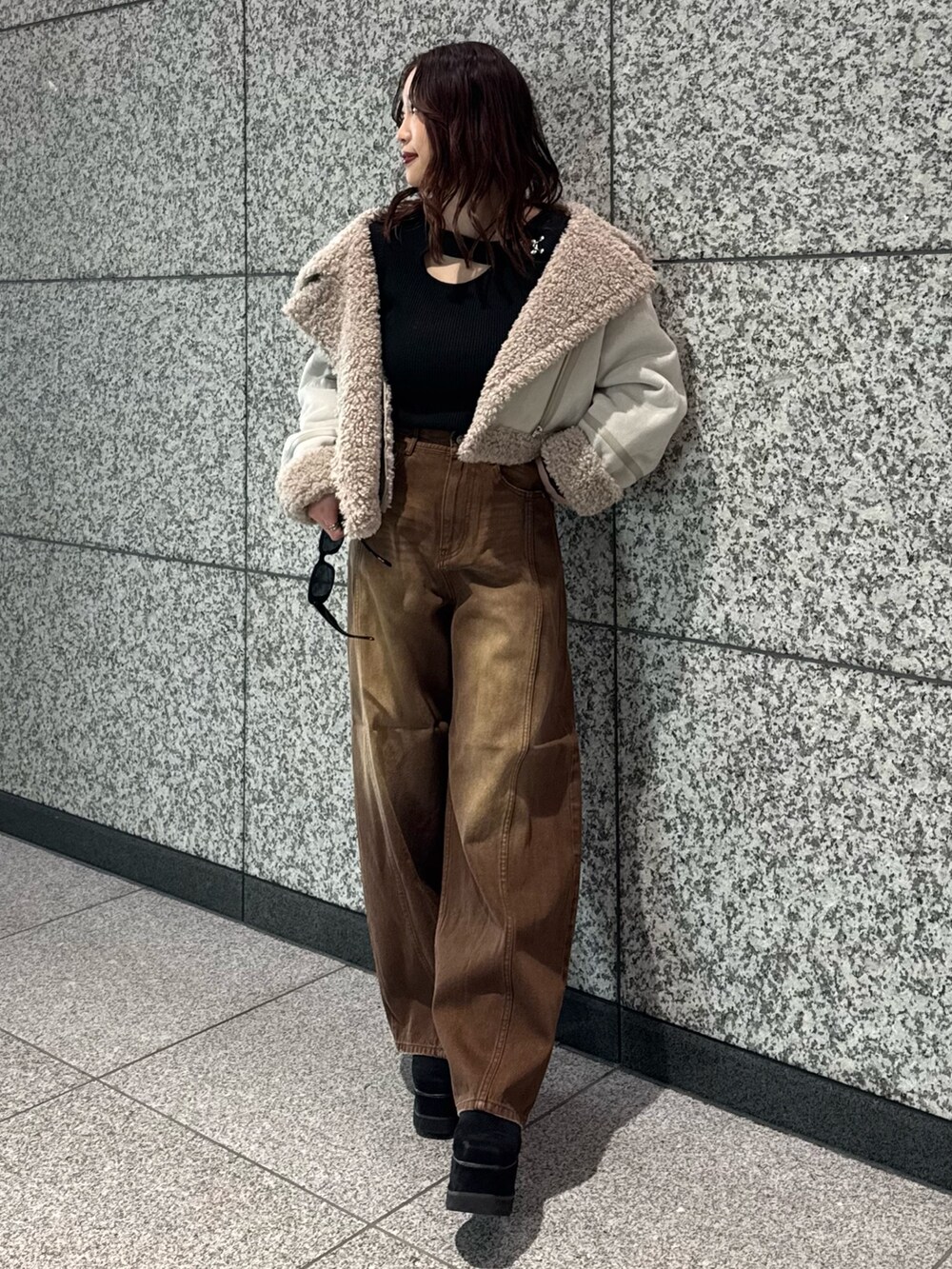 ブラック系のニット/セーター、ホワイト系のムートンコート、ブラウン系のデニムパンツを着用したレディースの冬コーディネートの4枚目の写真