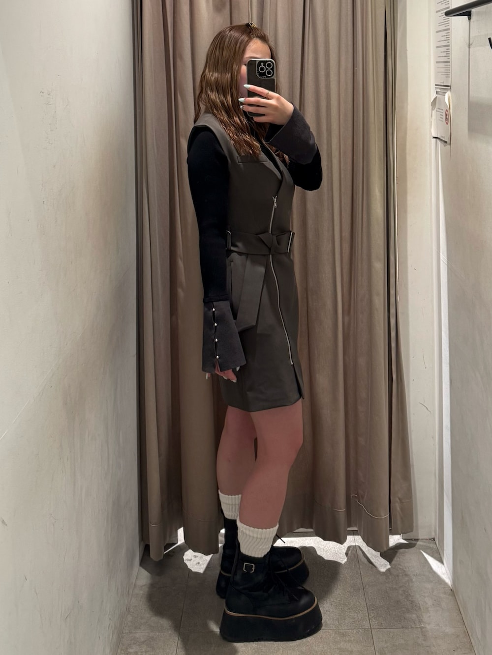 グレー系のワンピース、ブラック系のニット/セーター、ブラック系のブーツを着用したレディースの冬コーディネートの2枚目の写真