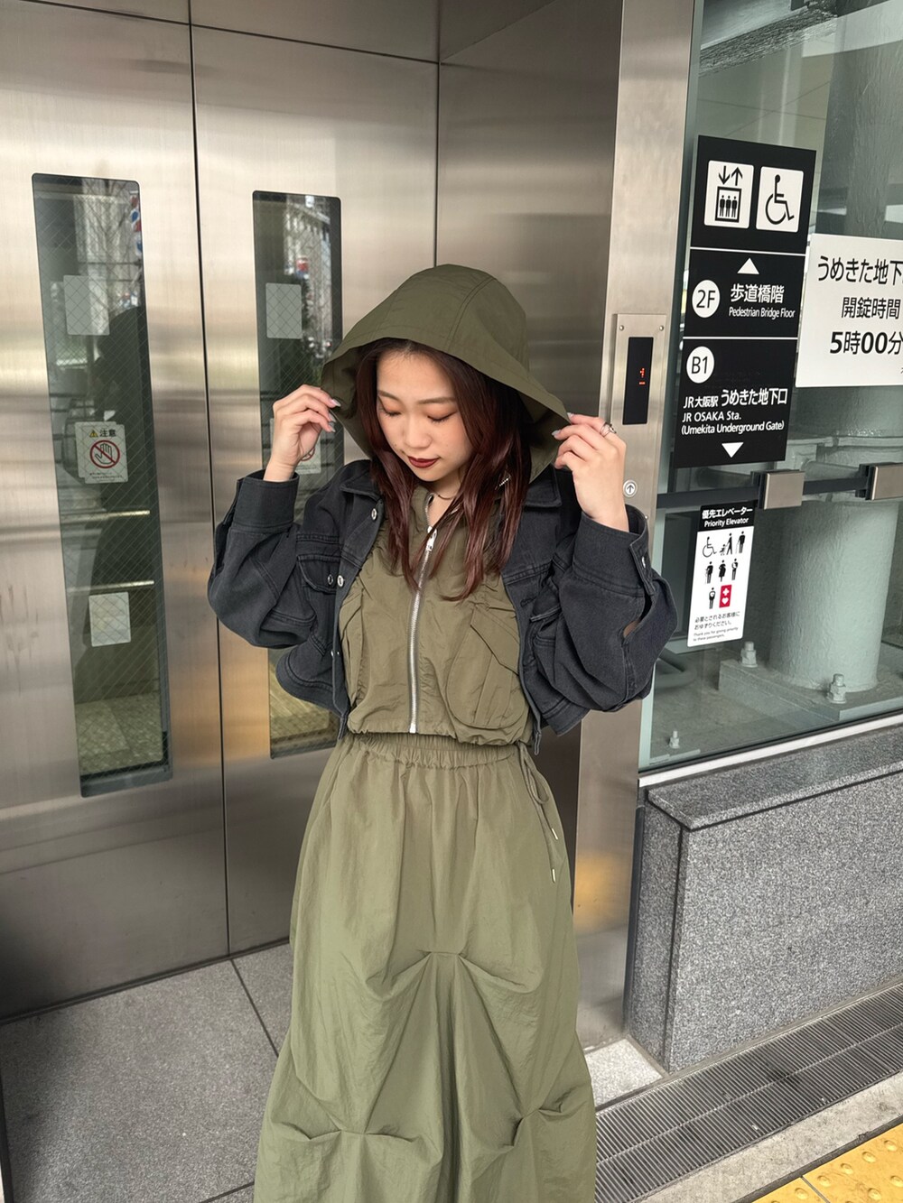 ブラック系のデニムジャケット、ベージュ系のベスト、グリーン系のスカートを着用したレディースの春コーディネートの4枚目の写真