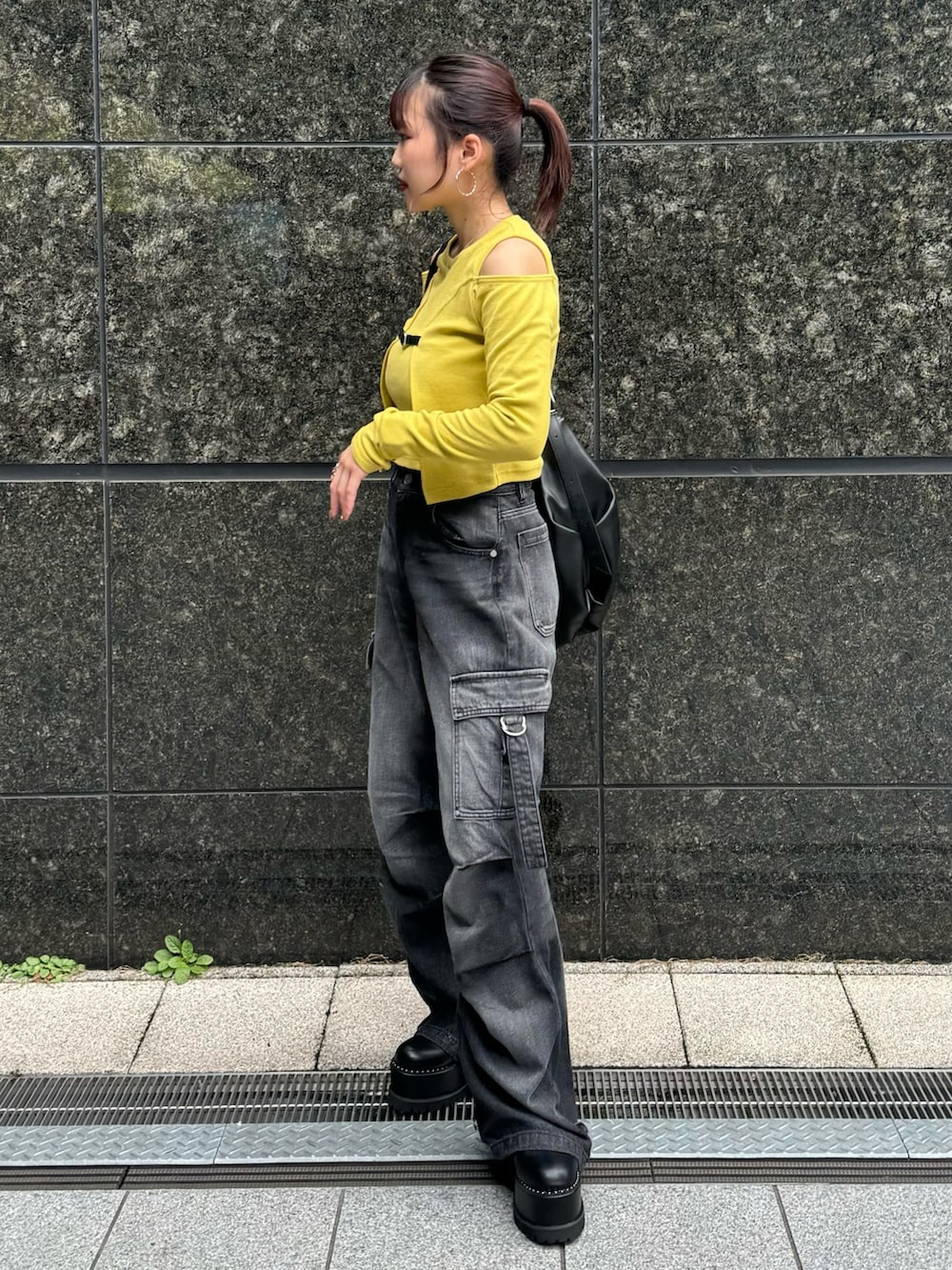 イエロー系のTシャツ/カットソー、ブラック系のデニムパンツ、ブラック系のブーツを着用したレディースの秋コーディネートの4枚目の写真