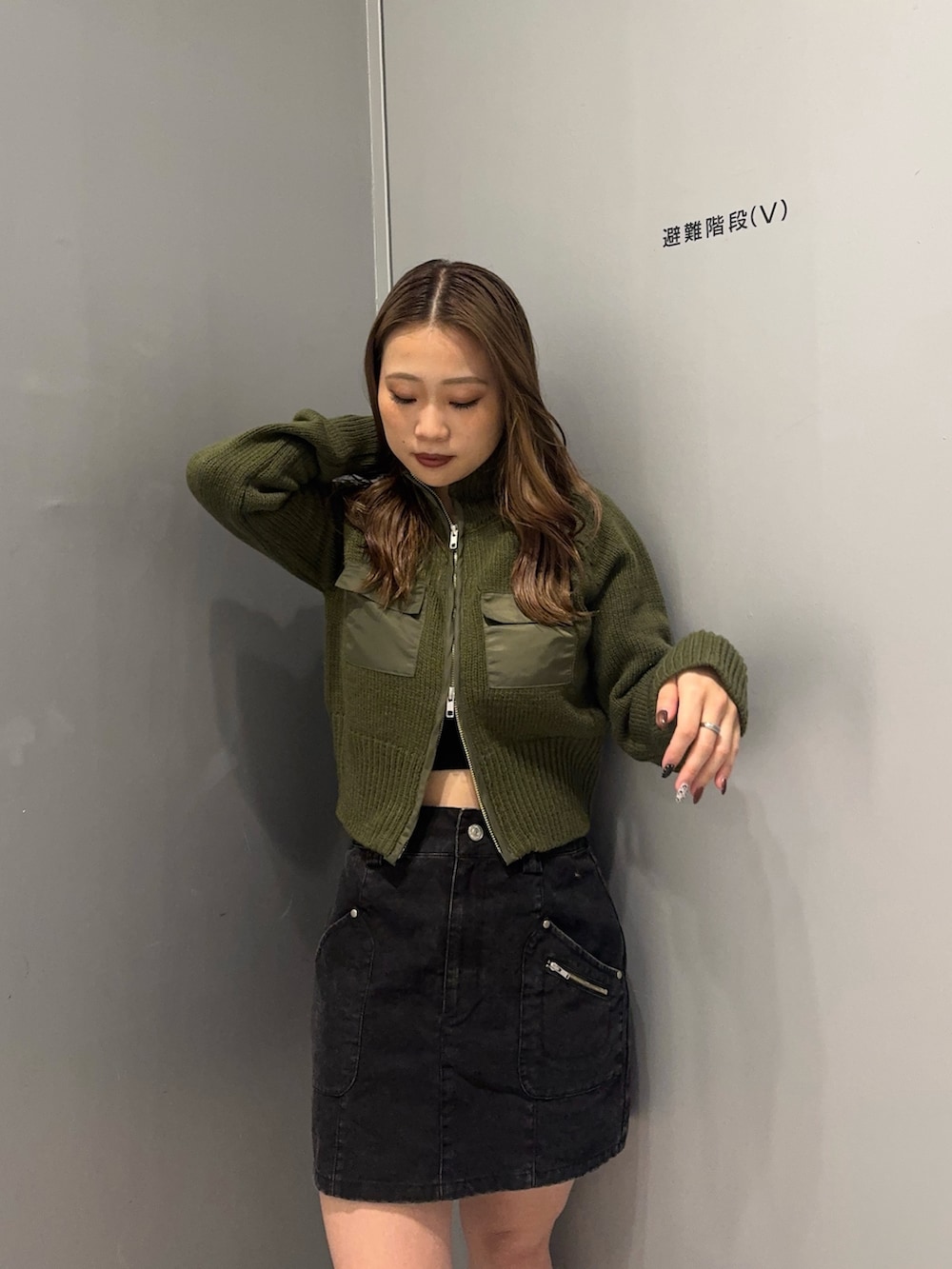 ブラック系のスカート、グリーン系のニット/セーター、ブラック系のブーツを着用したレディースの秋コーディネートの4枚目の写真