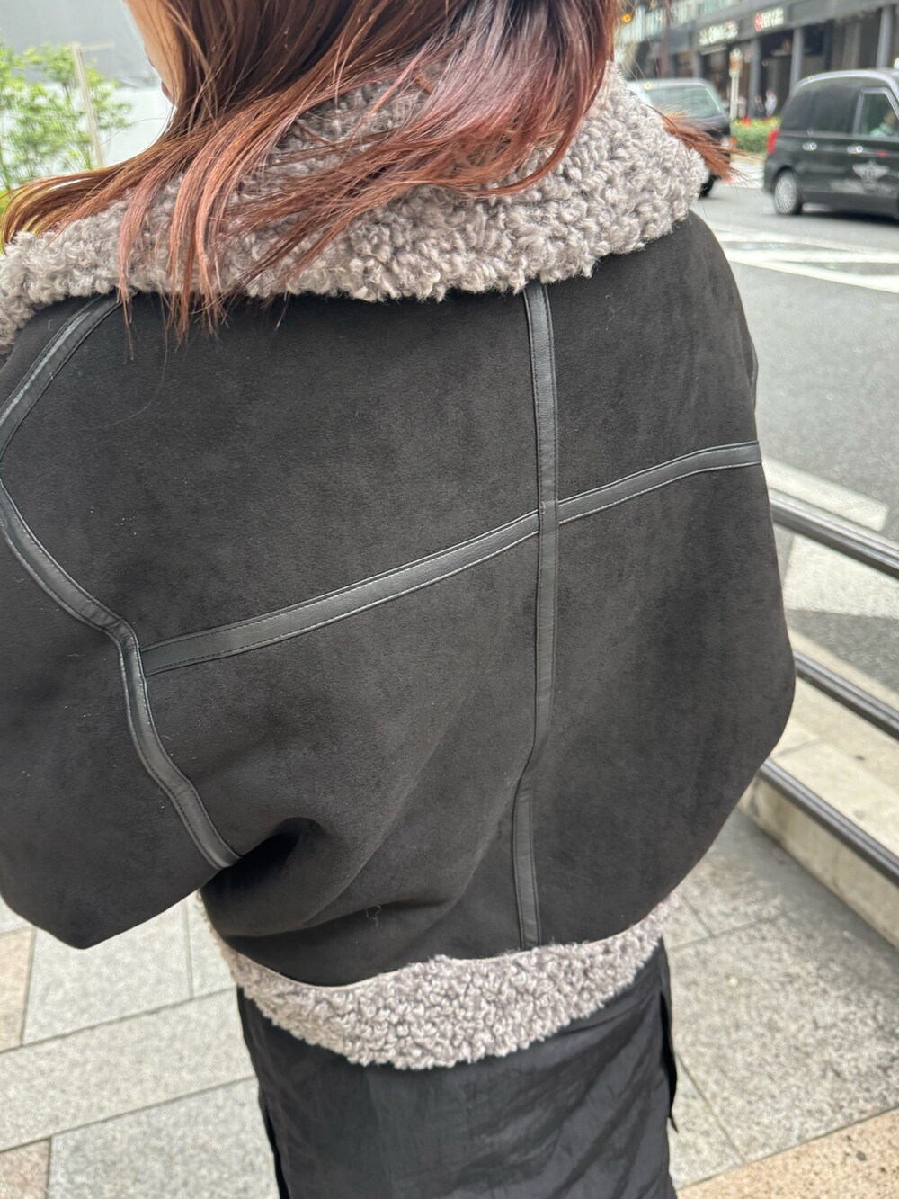 ブラック系のムートンコート、オレンジ系のニット/セーター、ブラック系のスカートを着用したレディースの冬コーディネートの6枚目の写真