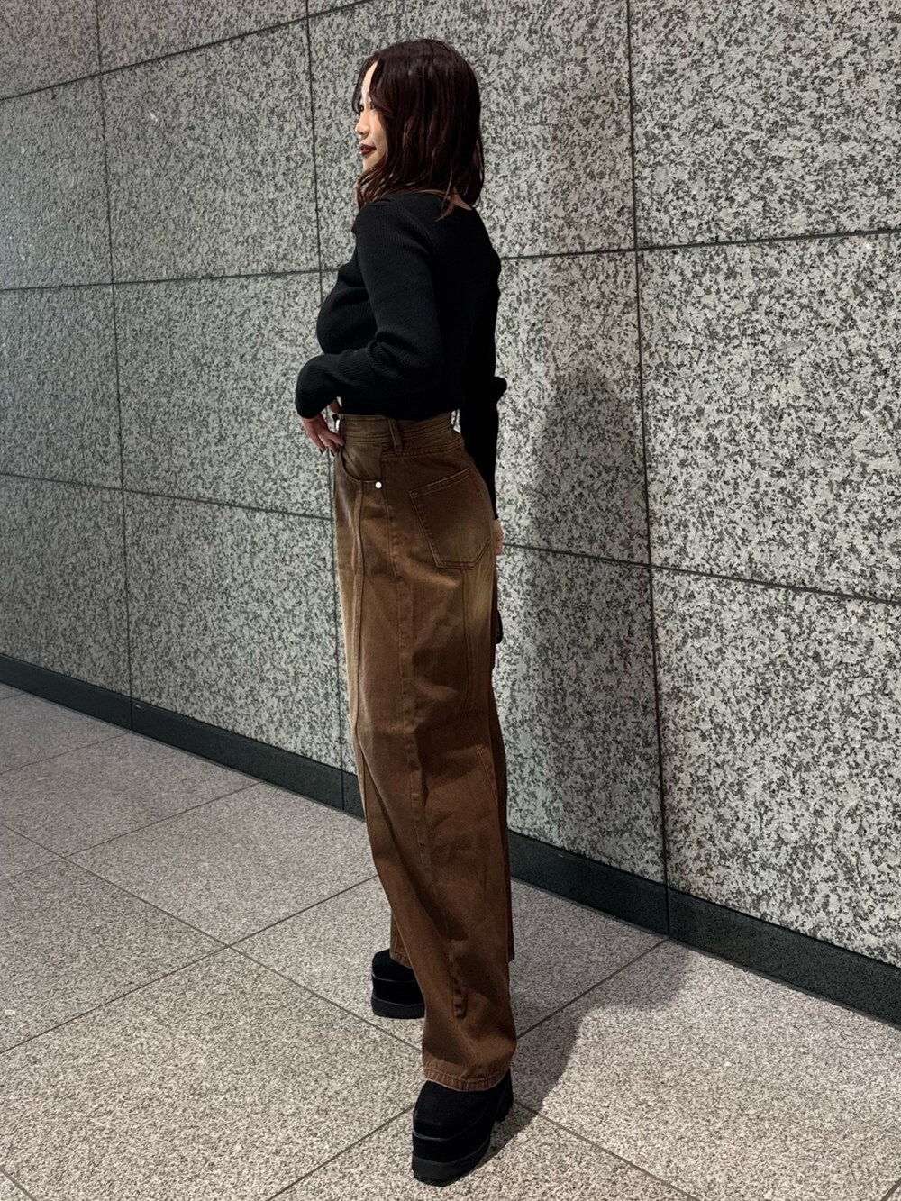 ブラック系のニット/セーター、ブラウン系のデニムパンツ、ブラック系のブーツを着用したレディースの冬コーディネートの2枚目の写真