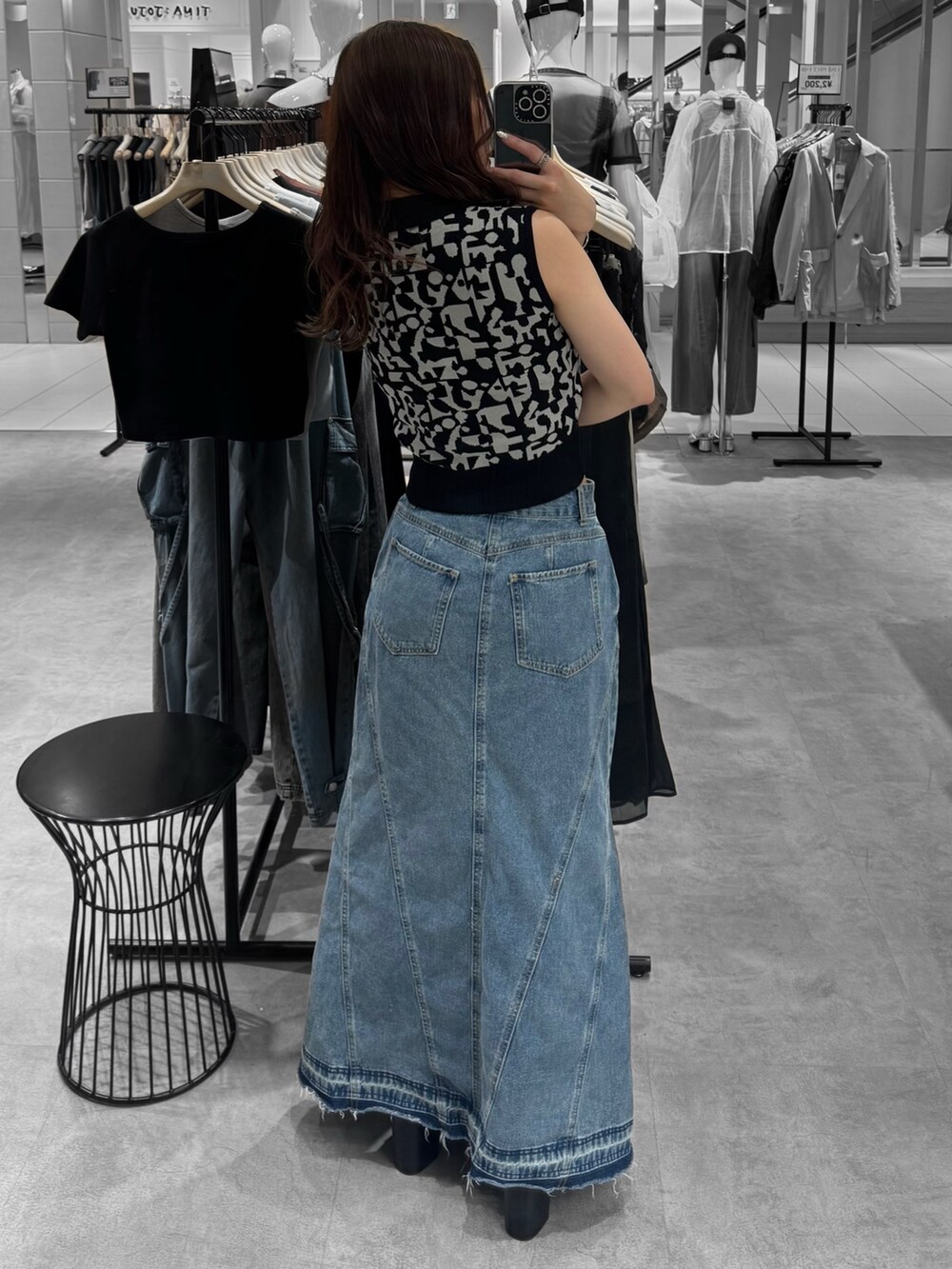 ブラック系のニット/セーター、ブルー系のデニムスカート、ブラック系のサンダルを着用したレディースの夏コーディネートの3枚目の写真