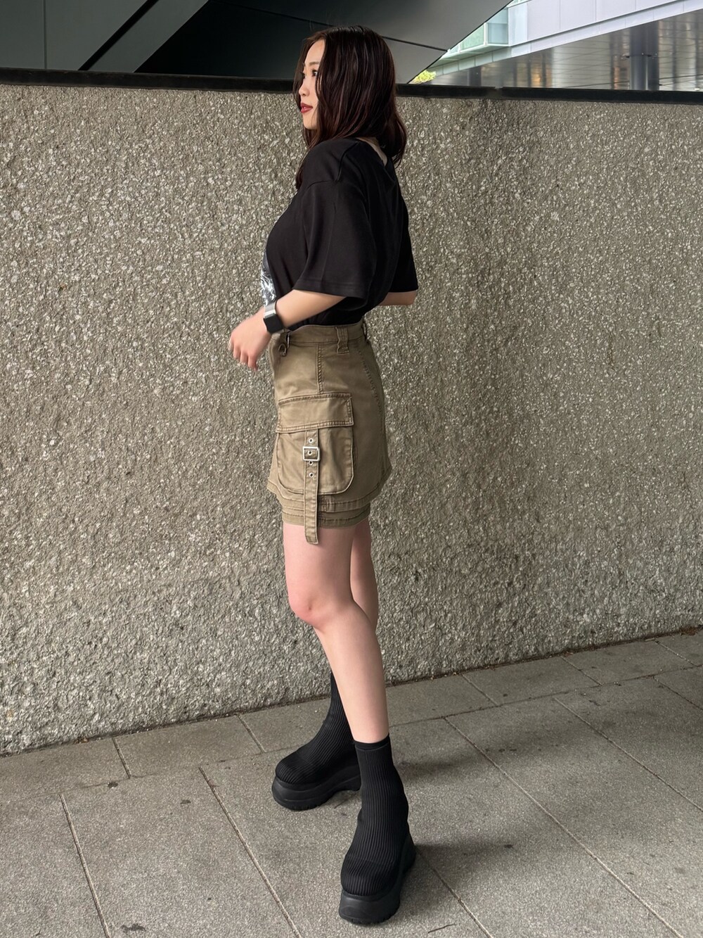 ブラック系のTシャツ/カットソー、ベージュ系のスカート、ブラック系のブーツを着用したレディースの春コーディネートの2枚目の写真