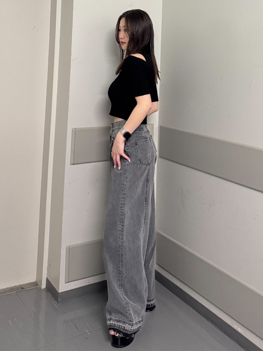 ブラック系のデニムパンツ、ブラック系のニット/セーター、ブラック系のサンダルを着用したレディースの春コーディネートの2枚目の写真