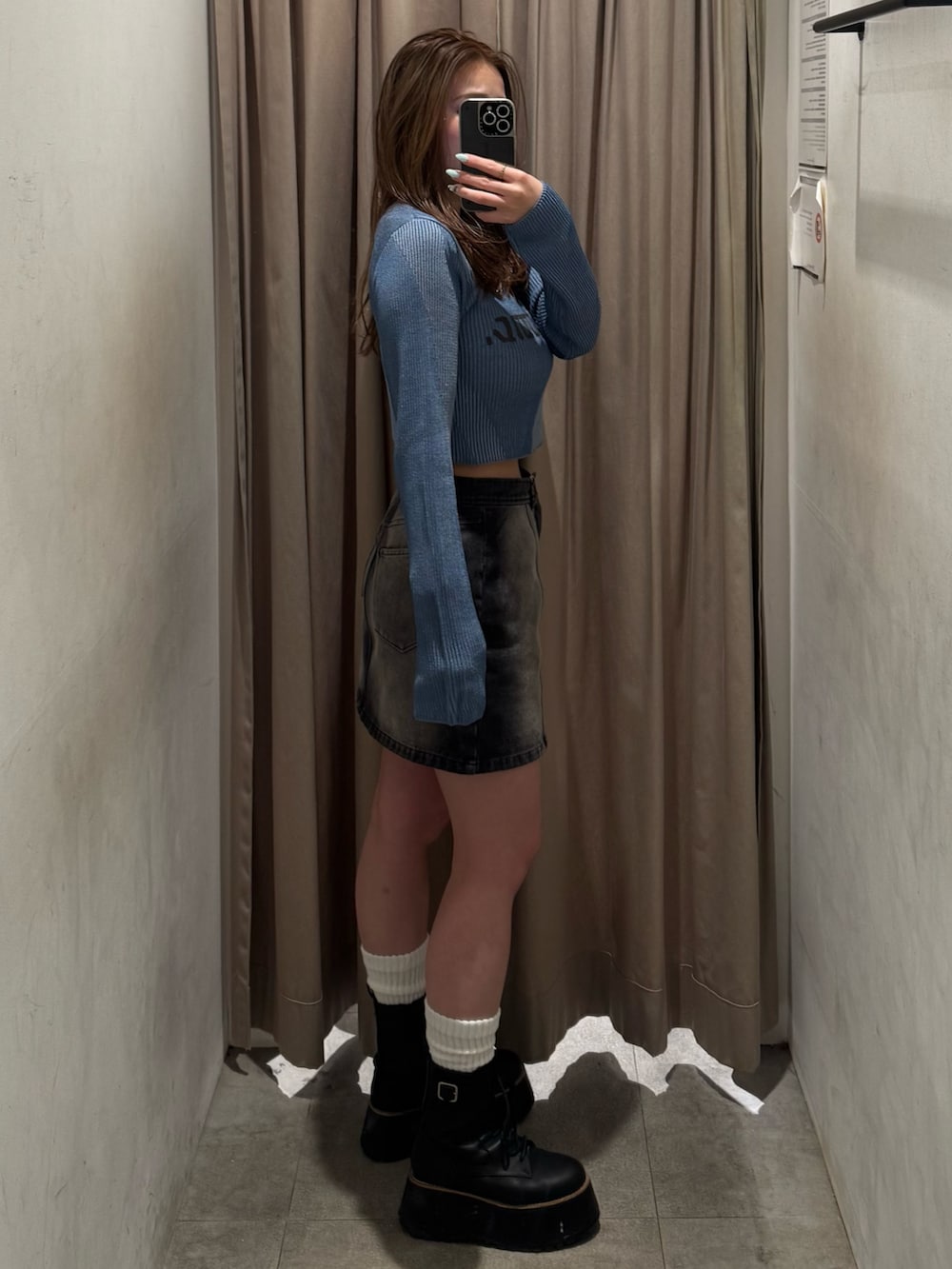 ブラック系のデニムスカート、ブルー系のニット/セーター、ブラック系のブーツを着用したレディースの冬コーディネートの2枚目の写真