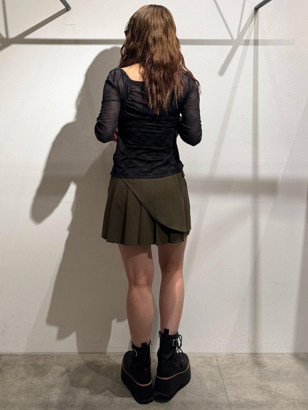 グリーン系のスカート、ブラック系のTシャツ/カットソー、ブラック系のブーツを着用したレディースの夏コーディネートの3枚目の写真