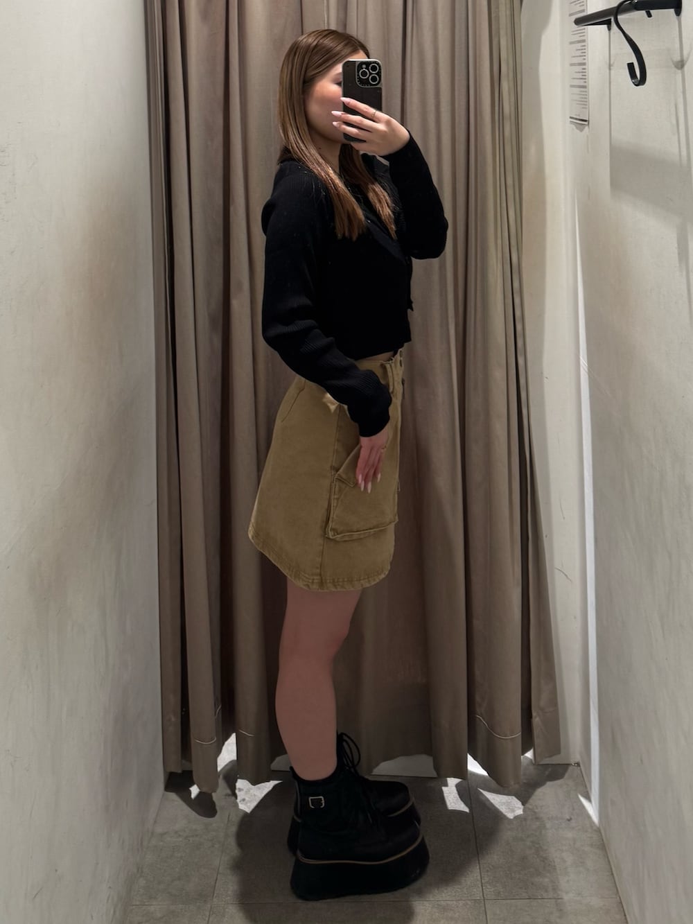 ベージュ系のスカート、ブラック系のニット/セーター、ブラック系のブーツを着用したレディースの春コーディネートの2枚目の写真