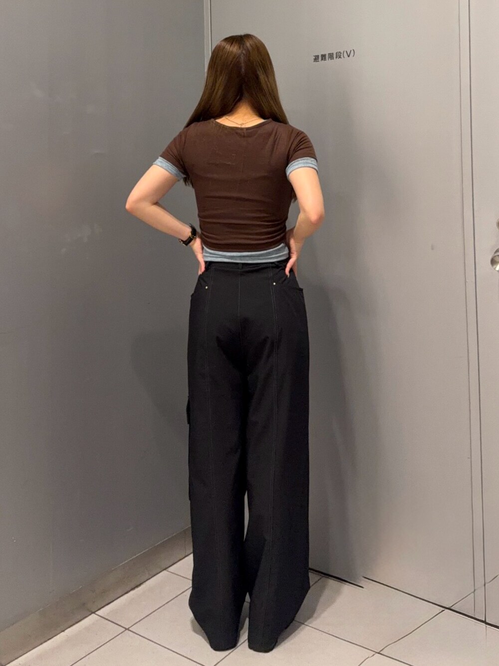 ブラック系のスラックス、ブラウン系のTシャツ/カットソー、ブラック系のブーツを着用したレディースの春コーディネートの3枚目の写真