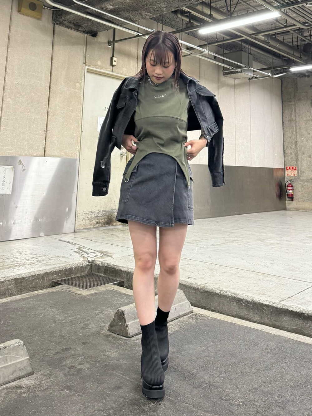 ブラック系のデニムジャケット、ブラック系のスカート、グリーン系のTシャツ/カットソーを着用したレディースの夏コーディネートの2枚目の写真