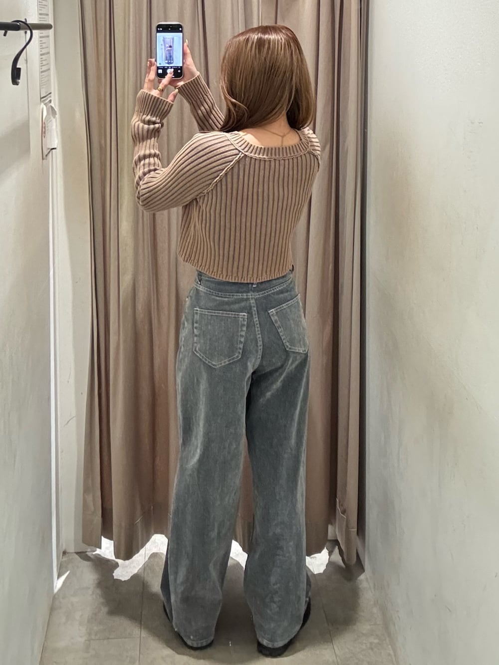 グレー系のデニムパンツ、ベージュ系のニット/セーター、ブラック系のブーツを着用したレディースの冬コーディネートの3枚目の写真