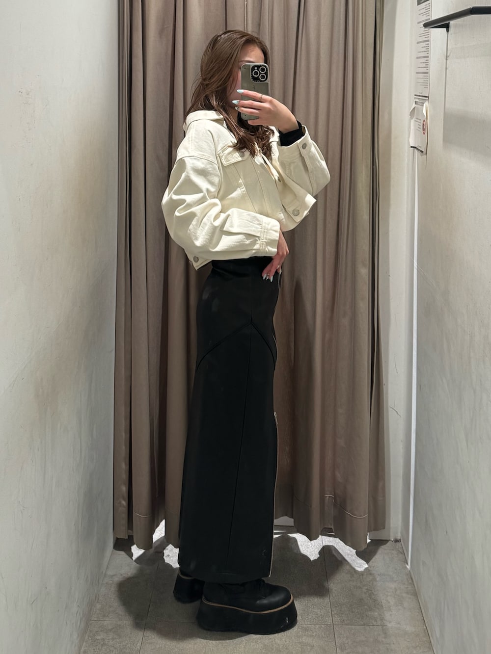 ブラック系のスカート、ホワイト系のデニムジャケット、ブラック系のブーツを着用したレディースの冬コーディネートの2枚目の写真