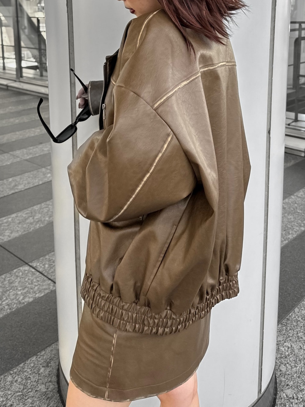 ブラック系のTシャツ/カットソー、ブラウン系のライダースジャケット、ブラウン系のスカートを着用したレディースの秋コーディネートの6枚目の写真