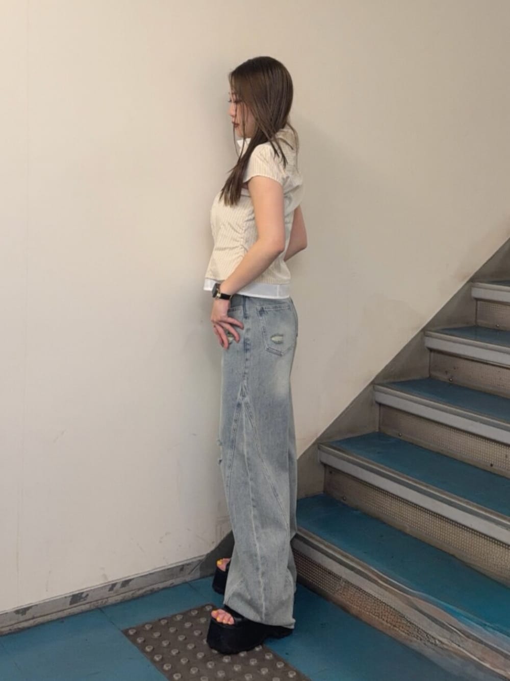 ブルー系のデニムパンツ、ブラック系のブーツ、イエロー系のシャツ/ブラウスを着用したレディースの夏コーディネートの2枚目の写真