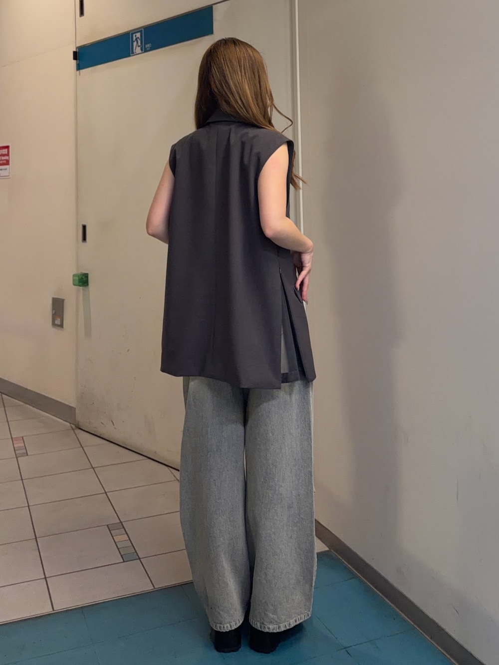 ブルー系のデニムパンツ、グレー系のベスト、ブラック系のキャミソールを着用したレディースの春コーディネートの3枚目の写真