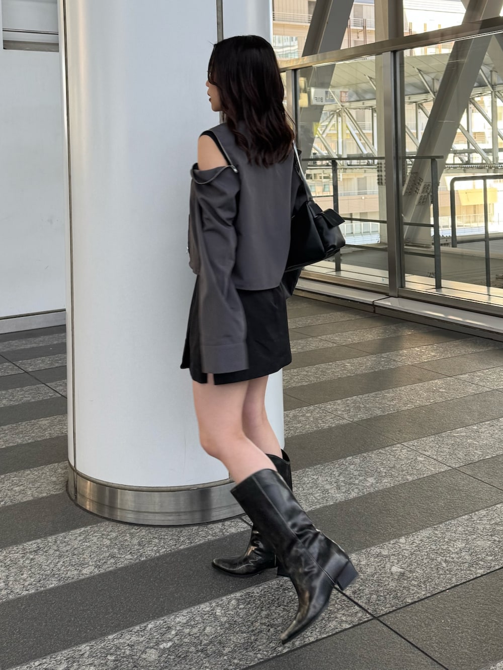 グレー系のシャツ/ブラウス、ブラック系のスカート、ブラウン系のブーツを着用したレディースの春コーディネートの2枚目の写真