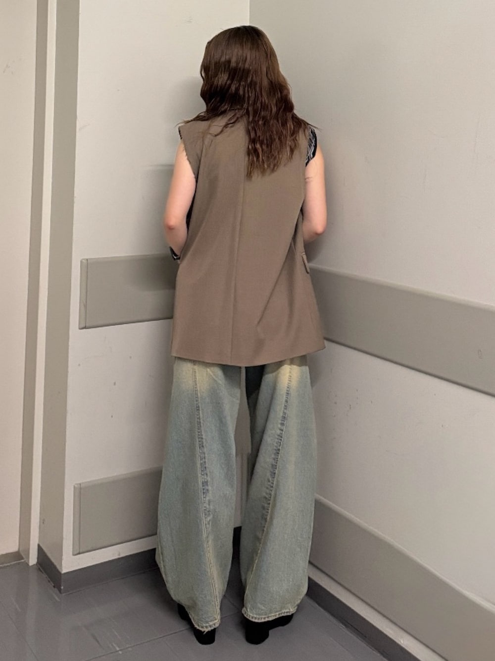 ブラック系のタンクトップ、ブラウン系のベスト、ブルー系のデニムパンツを着用したレディースの夏コーディネートの3枚目の写真