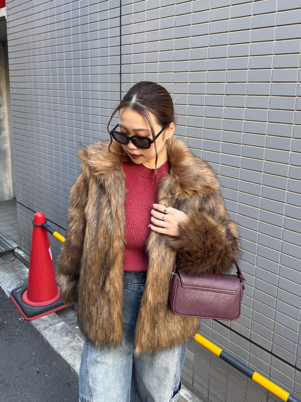 ブルー系のデニムパンツ、レッド系のニット/セーター、ブラウン系のその他アウターを着用したレディースの冬コーディネートの4枚目の写真