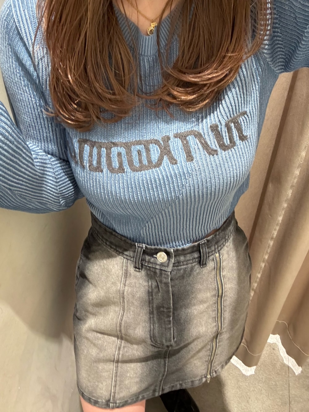 ブラック系のデニムスカート、ブルー系のニット/セーター、ブラック系のブーツを着用したレディースの冬コーディネートの5枚目の写真