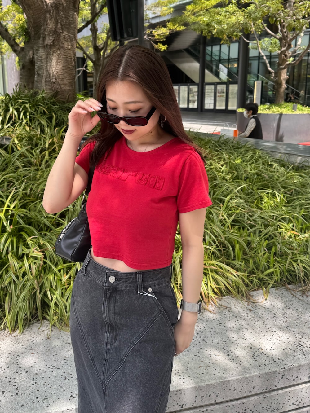 レッド系のTシャツ/カットソー、ブラック系のデニムスカート、ブラック系のブーツを着用したレディースの春コーディネートの4枚目の写真