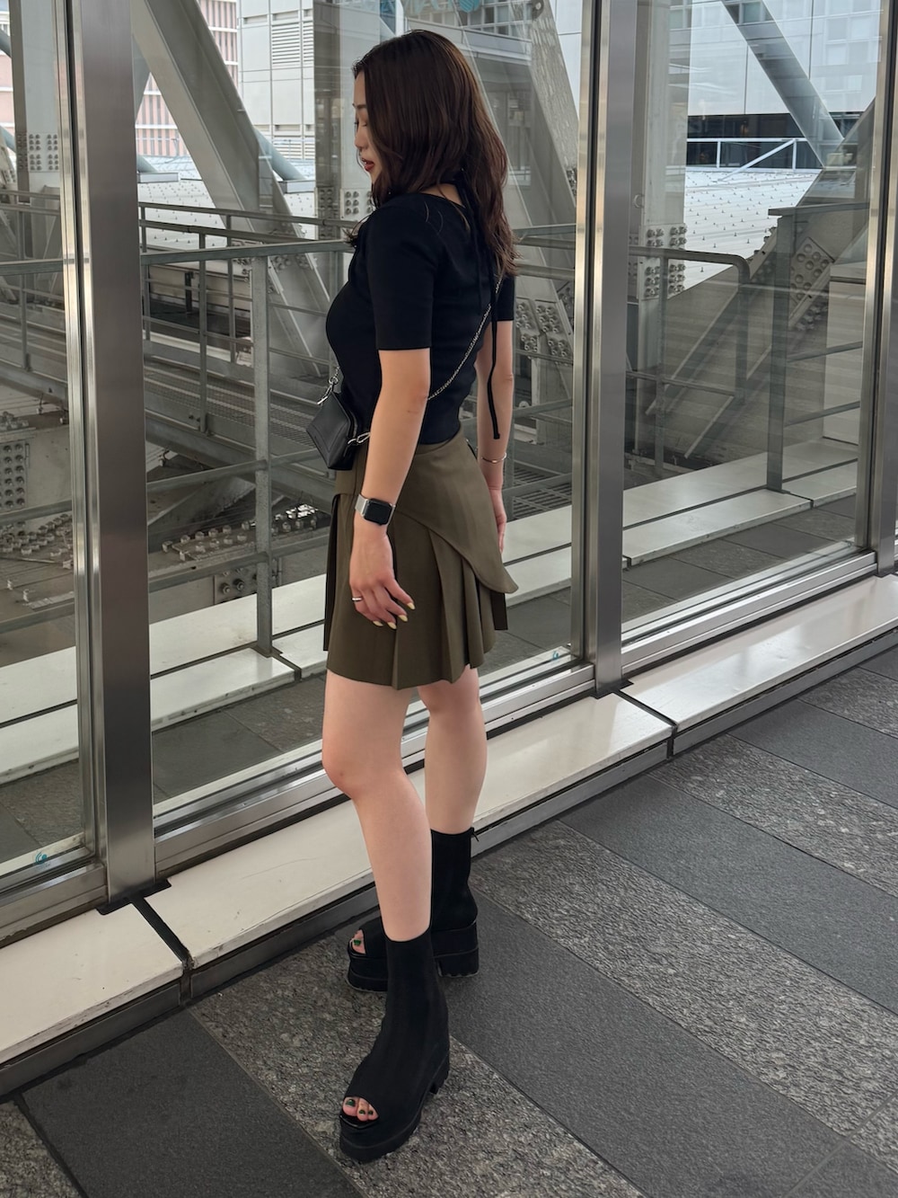 ブラック系のサンダル、グリーン系のスカート、ブラック系のTシャツ/カットソーを着用したレディースの夏コーディネートの2枚目の写真