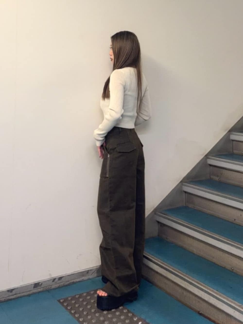 ブラック系のブーツ、ブラウン系のカーゴパンツ、ホワイト系のニット/セーターを着用したレディースの秋コーディネートの2枚目の写真