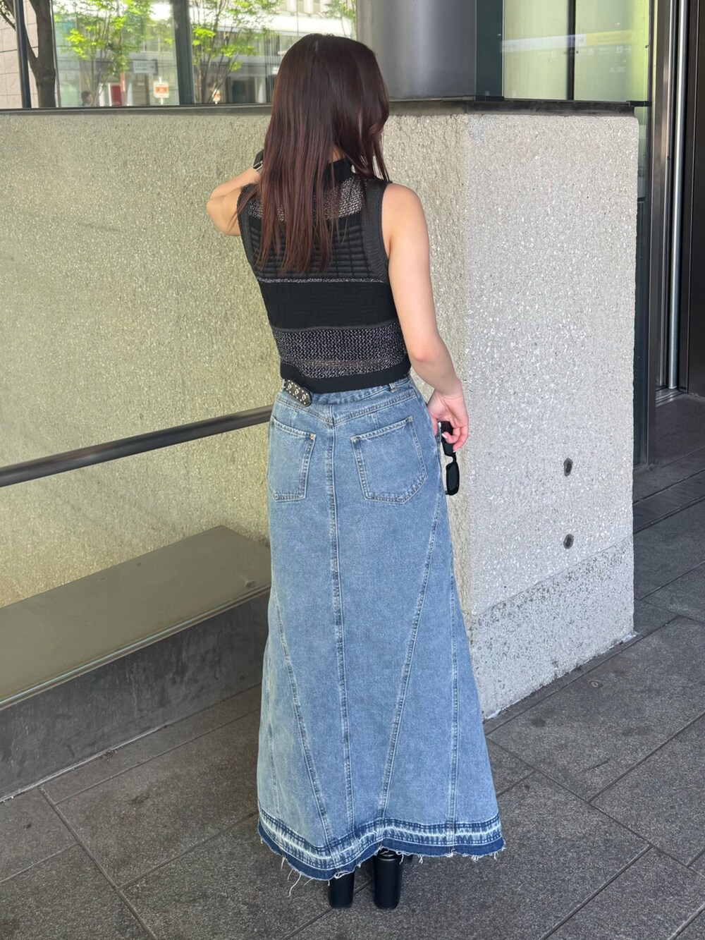 ブルー系のデニムスカート、ブラック系のタンクトップ、ブラック系のサンダルを着用したレディースの春コーディネートの3枚目の写真