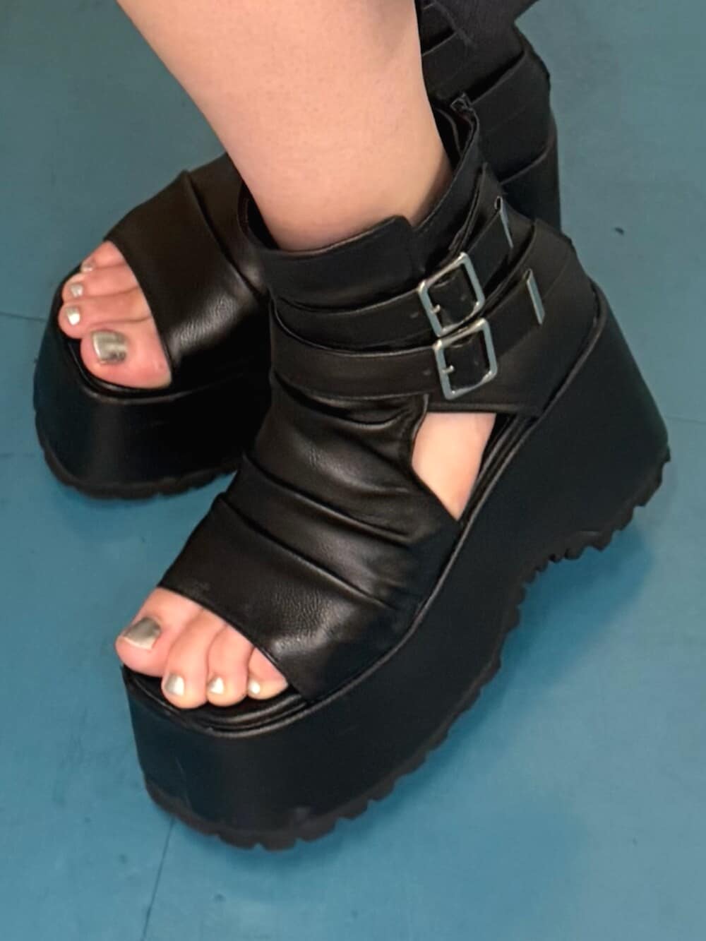 ブラック系のブーツ、ブラック系のニット/セーター、パープル系のデニムパンツを着用したレディースの夏コーディネートの5枚目の写真