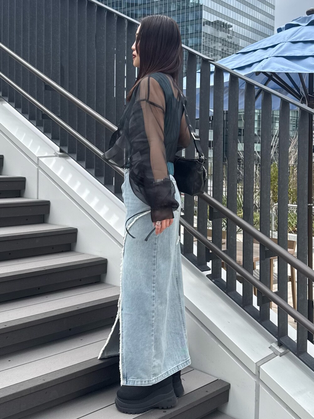 ブルー系のデニムスカート、ブラック系のシャツ/ブラウス、ブルー系のタンクトップを着用したレディースの春コーディネートの2枚目の写真