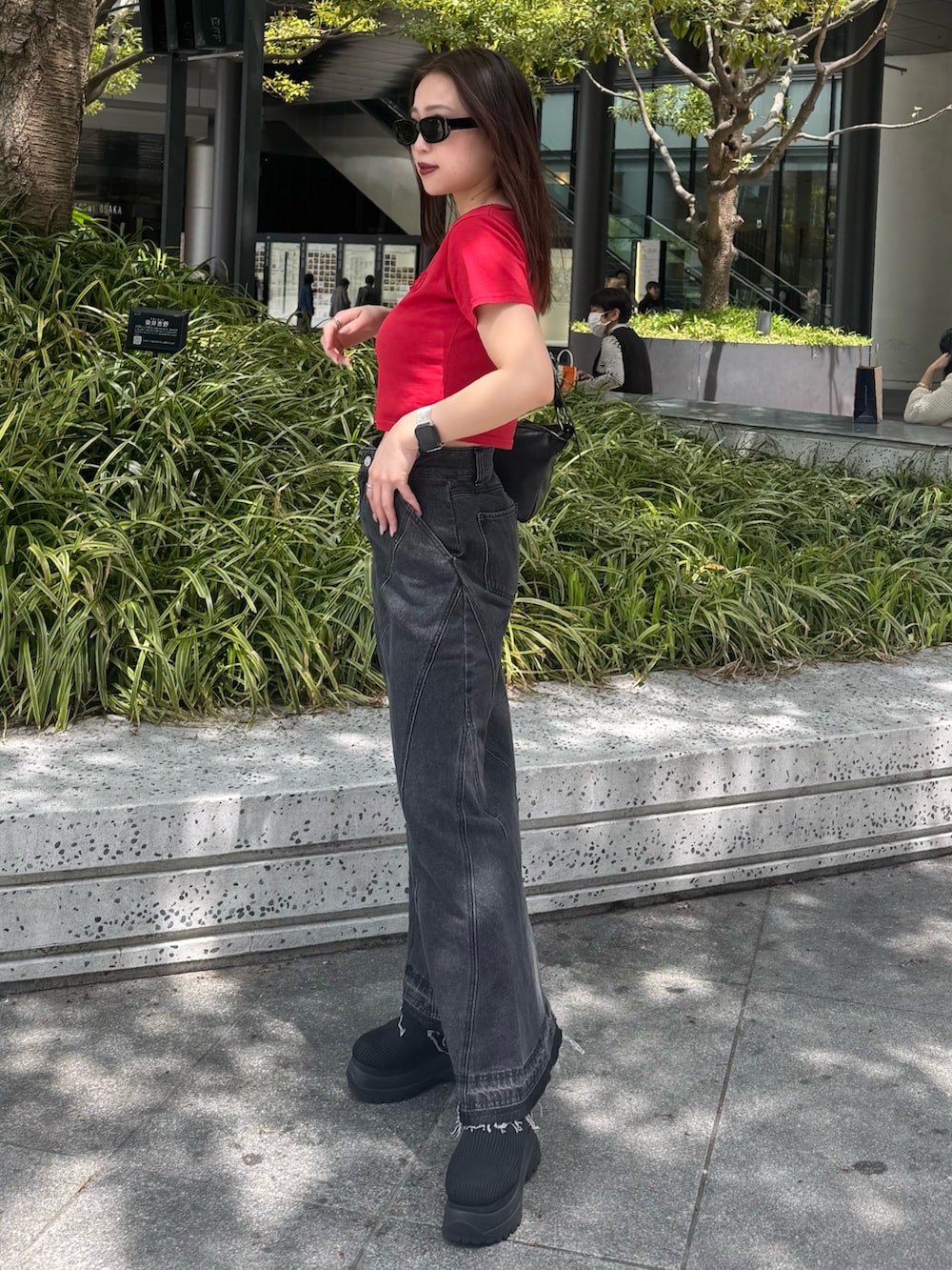 レッド系のTシャツ/カットソー、ブラック系のデニムスカート、ブラック系のブーツを着用したレディースの春コーディネートの2枚目の写真