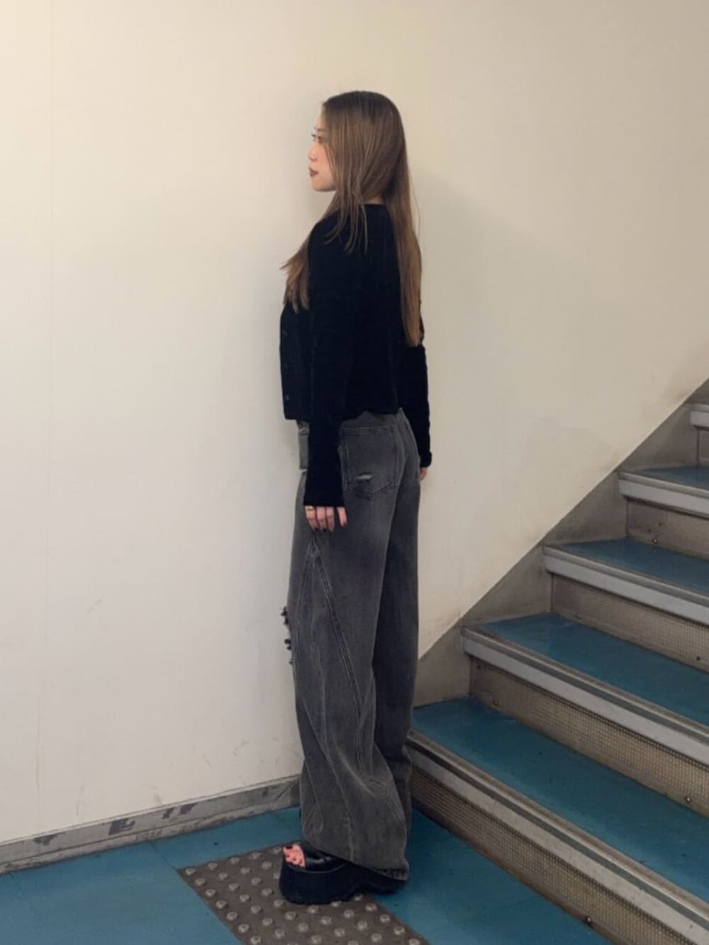 グレー系のデニムパンツ、ブラック系のブーツ、ブラック系のアンサンブルを着用したレディースの秋コーディネートの2枚目の写真