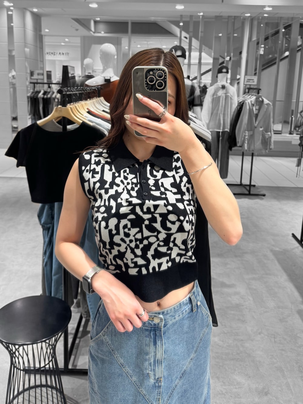 ブラック系のニット/セーター、ブルー系のデニムスカート、ブラック系のサンダルを着用したレディースの夏コーディネートの4枚目の写真