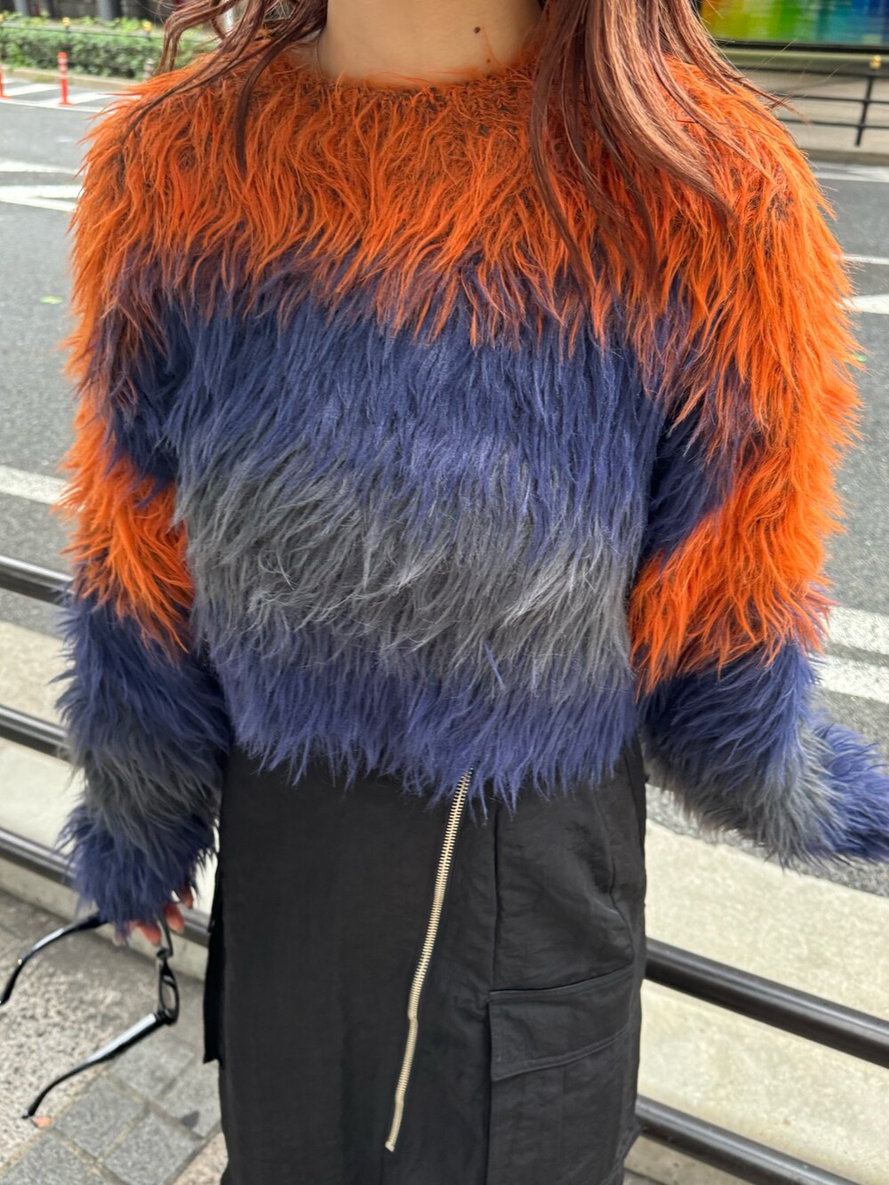 オレンジ系のニット/セーター、ブラック系のスカート、ブラウン系のブーツを着用したレディースの秋コーディネートの7枚目の写真