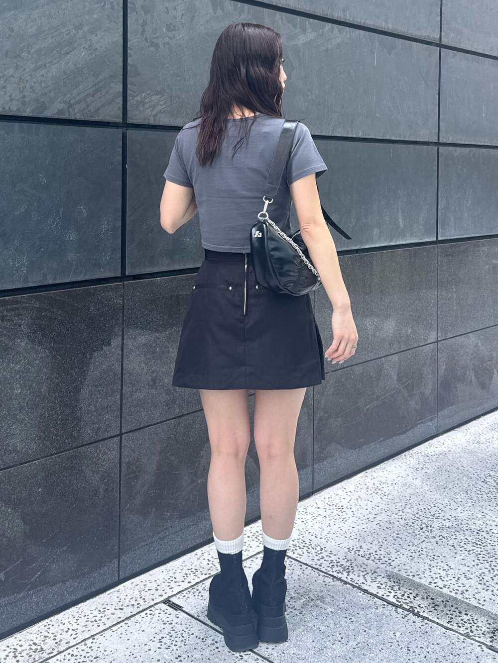 グレー系のTシャツ/カットソー、ブラック系のスカート、ブラック系のブーツを着用したレディースの春コーディネートの3枚目の写真