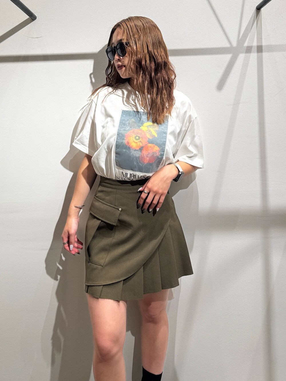 グリーン系のスカート、ホワイト系のTシャツ/カットソー、ブラック系のサンダルを着用したレディースの夏コーディネートの4枚目の写真